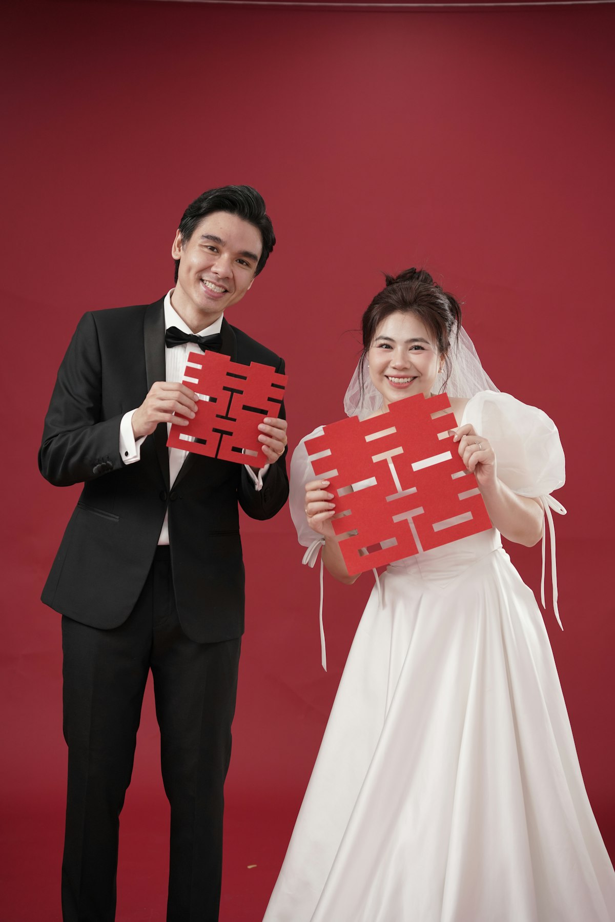 The couple holding red double-happiness cards