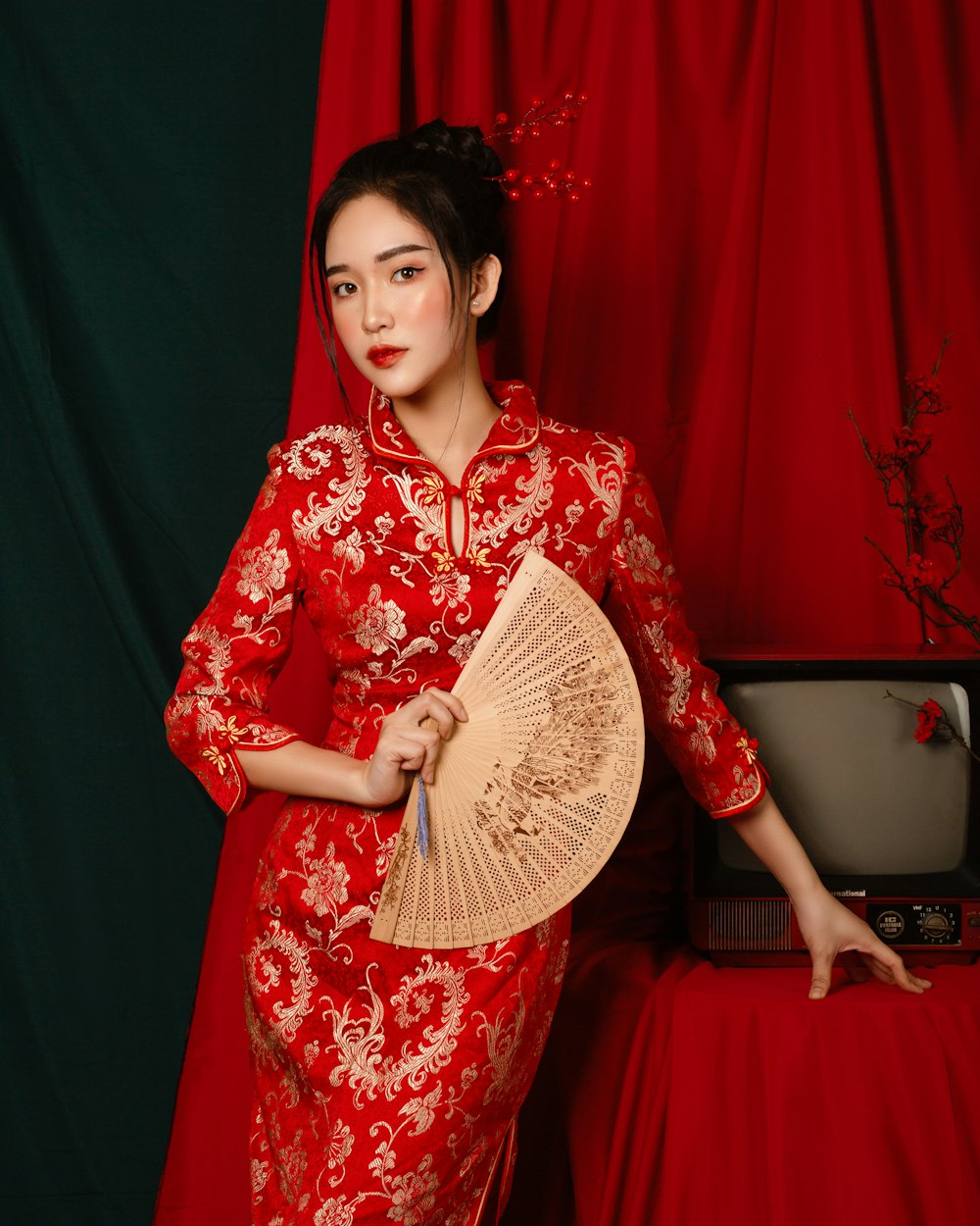 Zoey in a red gown holding a fan, dressed for the celebration